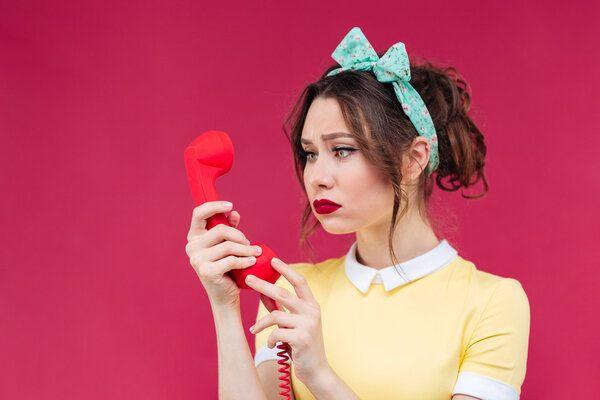 Грустная красивая женщина, использующая красный приемник и разговаривающая по телефону
