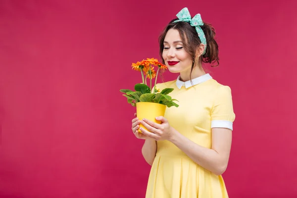 Gelukkig pinup meisje stam ding en ruikende oranje bloem in pot — Stockfoto