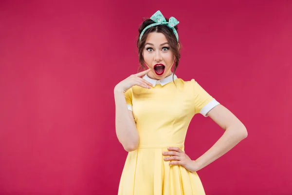 Förvånad Pinup flicka i gul klänning stående med munnen öppnas — Stockfoto