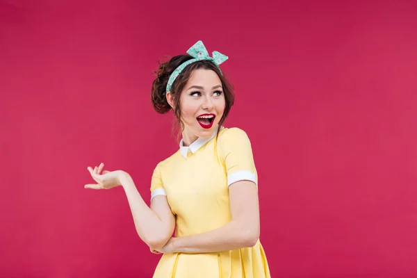 Vrolijke speelse pinup meisje in gele jurk wijzend — Stockfoto