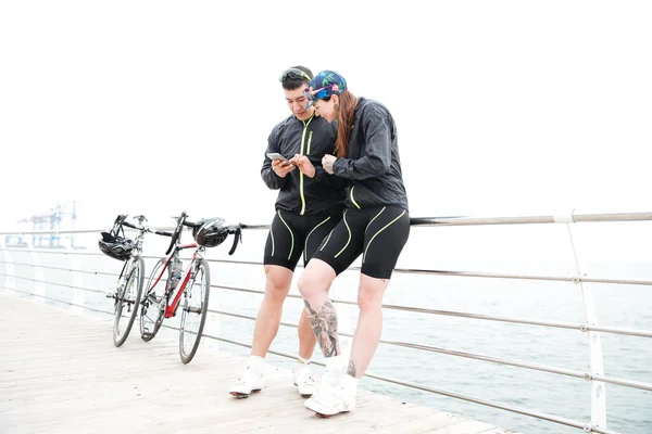 Pareja con bicicletas usando el teléfono móvil en el muelle juntos — Foto de Stock