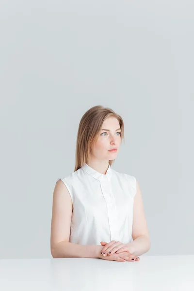 Jeune femme réfléchie assise à la table — Photo