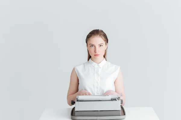 Mujer sentada en la mesa y escribiendo en la máquina retro — Foto de Stock