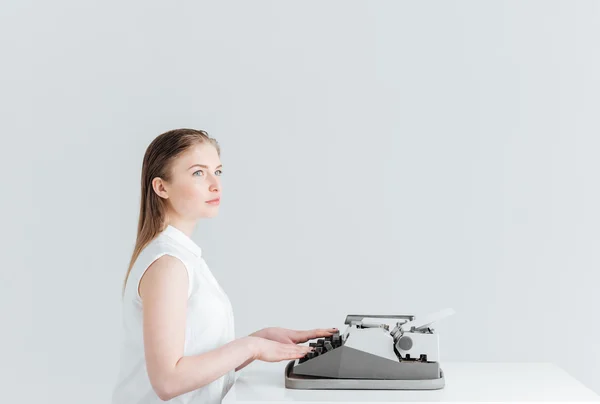 Mujer pensativa escribiendo en la máquina retro — Foto de Stock