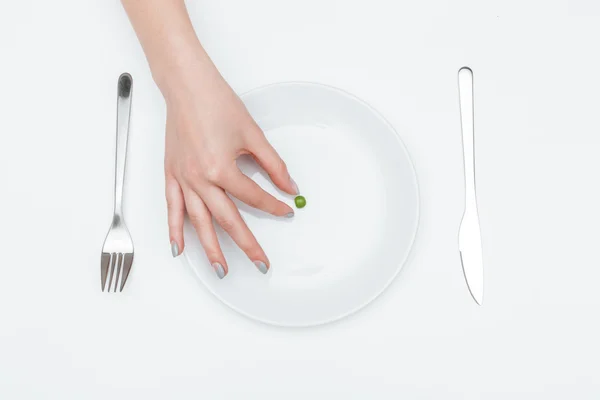 Un pisello verde sul piatto preso dalla mano della donna — Foto Stock