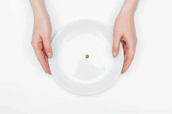 Assiette avec un pois vert tenu par les mains de la femme — Photo
