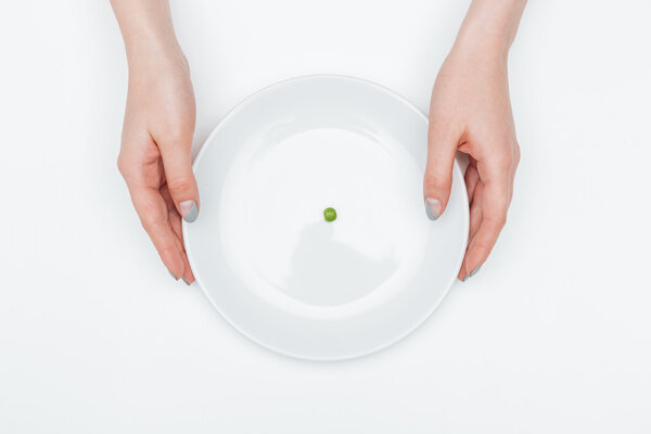Plate with one green pea holded by hands of woman