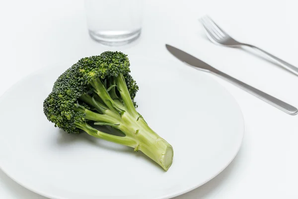 Glas water, vork, mes en broccoli op de plaat — Stockfoto