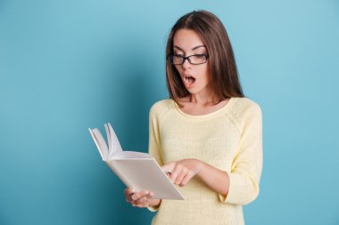 Kitap mavi arka plan üzerinde seyir sürpriz hayran güzel kız