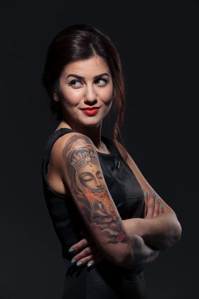 Joyeux tatoué jeune femme debout avec les bras croisés — Photo