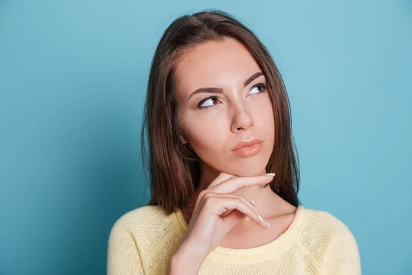 Närbild porträtt av fundersam tjej som funderar över blå bakgrund — Stockfoto