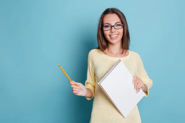 Śmiech wesoły ładny dziewczyna gospodarstwa notebook na niebieskim tle — Zdjęcie stockowe