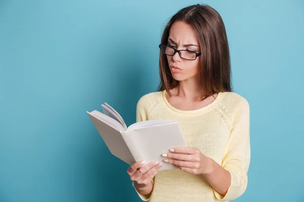 Młoda dziewczyna czytając książkę na niebieskim tle — Zdjęcie stockowe