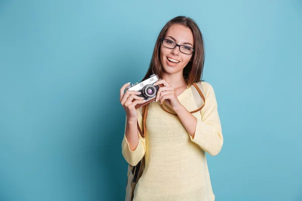 Девушка фотографирует с помощью фотокамеры на синем фоне — стоковое фото