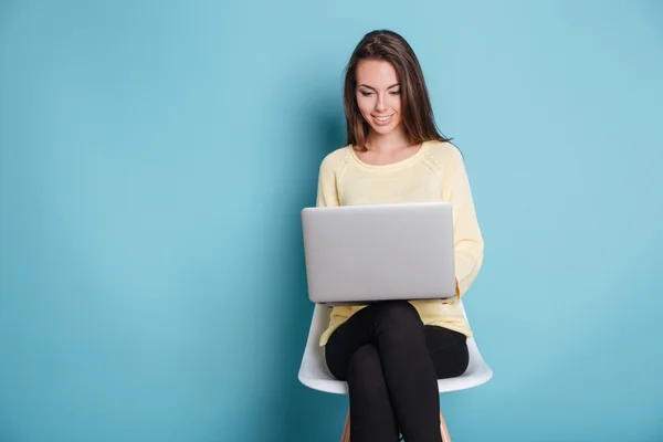 Chica joven hermosa inteligente usando el ordenador portátil sobre fondo azul — Foto de Stock