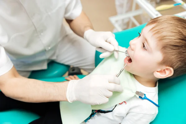 Tandarts behandeling van kleine jongen tanden met spiegel en haak — Stockfoto