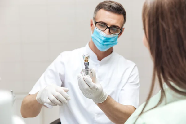 Стоматолог пояснює модель зубів пацієнтці — стокове фото
