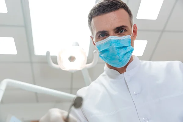 Manliga tandläkare att göra behandling tittar på kameran — Stockfoto
