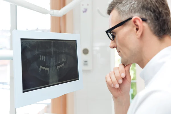 数字 x 射线电脑显示器上看牙的男性牙医 — 图库照片