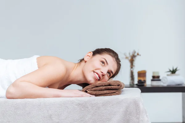 Felice bella giovane donna sorridente e sdraiata nel salone spa — Foto Stock
