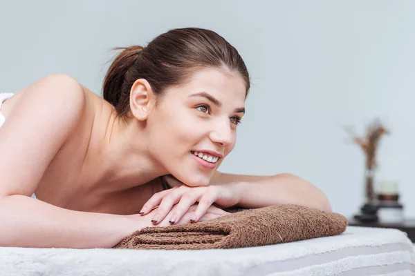 Lachende mooie vrouw liggend op een massagetafel in spa salon — Stockfoto