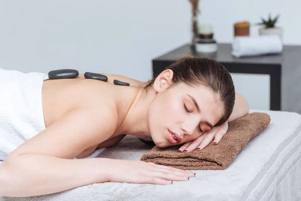 Mulher relaxante e recebendo massagem de pedra quente no salão de spa — Fotografia de Stock