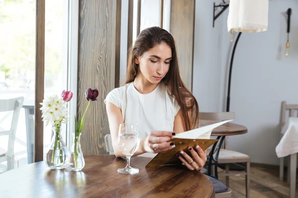 Красивая молодая женщина в ресторане читает меню — стоковое фото