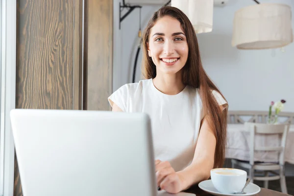 Pretty smiling business woman using laptop in restaurant — Stock Photo, Image