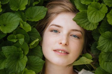 Yeşil yaprakları tarafından çevrili çekici ihale genç kadın