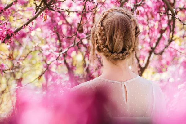 Blonde junge Frau steht im frühlingsblühenden Garten — Stockfoto