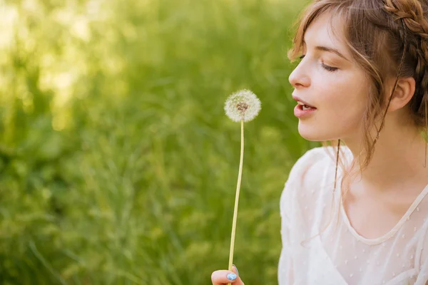 Lovely woman holding and blowing on dandelion outdoors — Stock Photo, Image