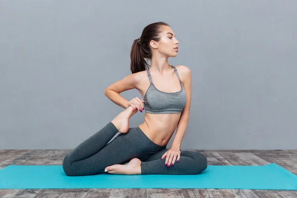 Giovane donna che fa esercizio yoga un piccione re gambe — Foto Stock