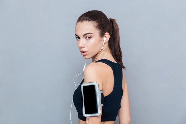 Крупный план портрета фитнес-девушки со смартфоном и наушниками — стоковое фото