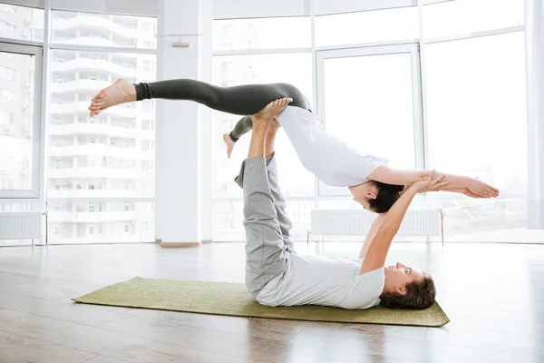 Peaceful young couple practicing acro yoga in studio together