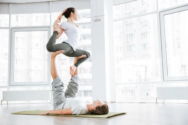 Concentrato giovane uomo e donna che fa acro yoga per le coppie — Foto Stock