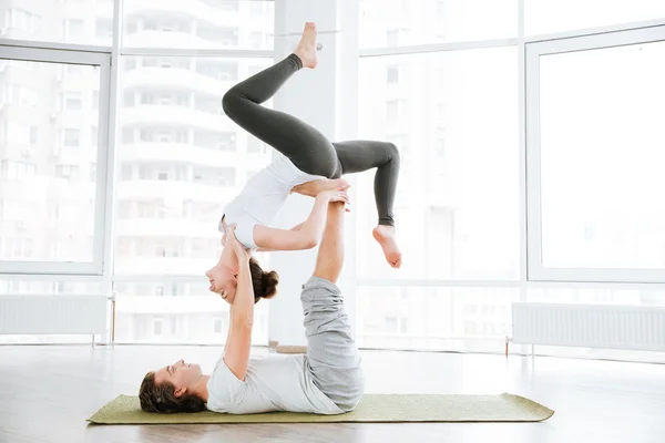 Pacified couple doing acro yoga in studio together