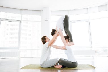 Adam ve iki kadın grubunda acro yoga yaparken