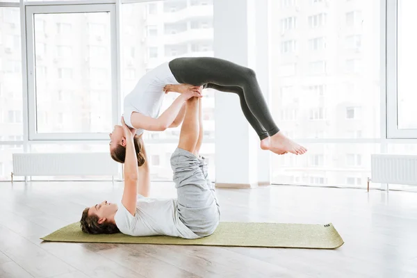 Young man and woman doing acro yoga in pair — Stock Photo, Image