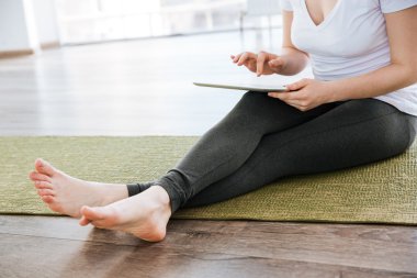 Yoga mat AMD tablet Studio'yu kullanarak oturan kadın