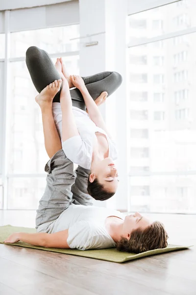 Young couple doing acro yoga exercises in studio together — Stock Photo, Image