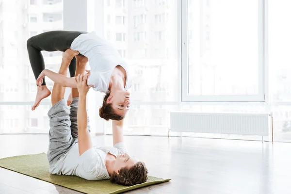 Pareja haciendo ejercicios de estiramiento en estudio de yoga —  Fotos de Stock