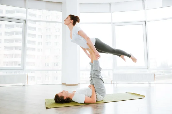 Beautiful young couple doing acro yoga in studio together