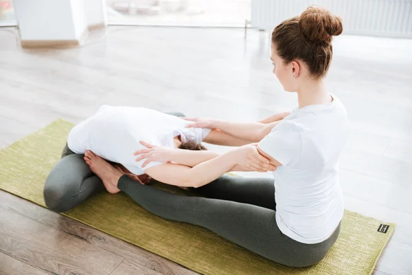 Two women sitting and stretching in yoga center