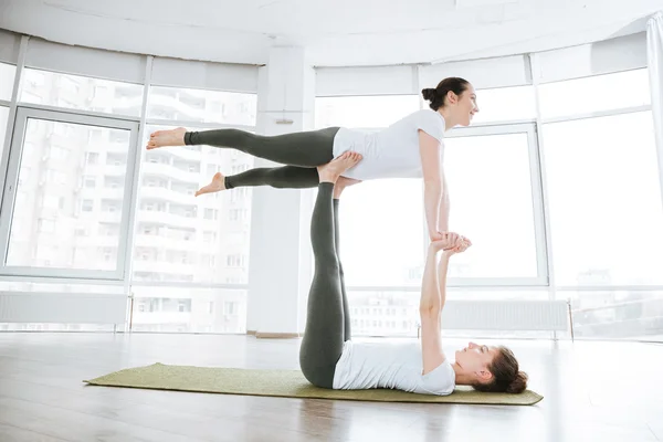 Due giovani donne attraenti in equilibrio e facendo acro yoga — Foto Stock