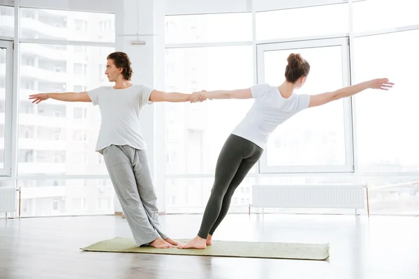 Jovem casal fazendo exercícios de alongamento no estúdio de ioga juntos — Fotografia de Stock
