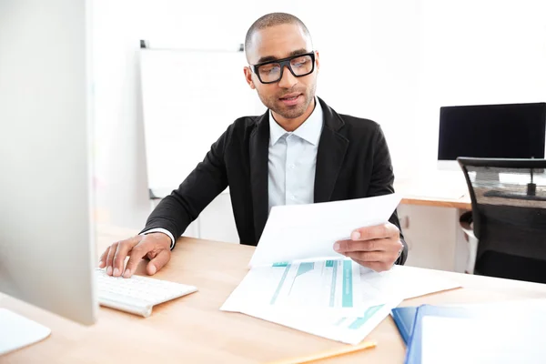 Schöner junger Geschäftsmann, der mit Dokumenten im Büro arbeitet — Stockfoto