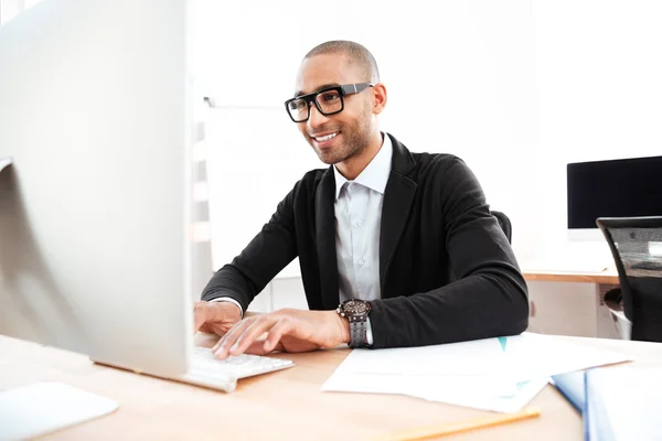 Lächelnder smarter Geschäftsmann, der im Büro mit dem Computer arbeitet — Stockfoto