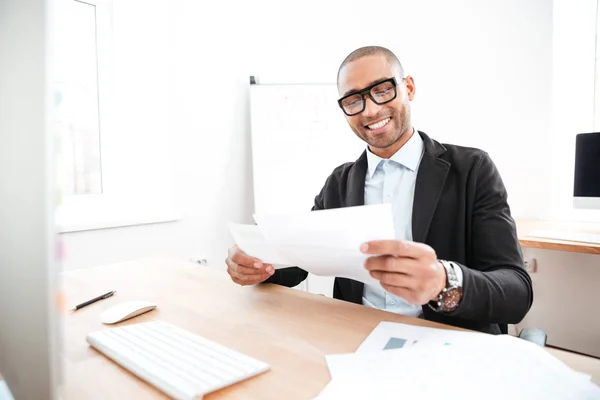 Glücklicher junger Geschäftsmann, der mit Papieren im Büro arbeitet — Stockfoto