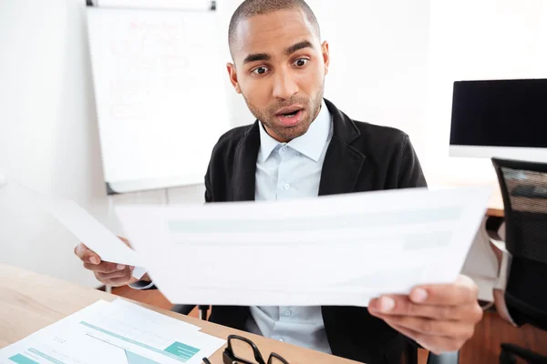 Shocked businessman looking at paper and holding eyeglasses — Stock Photo, Image