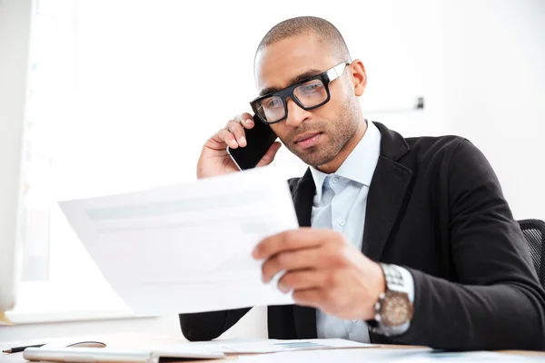 Nadenkend jonge zakenman kijken naar documenten in office — Stockfoto